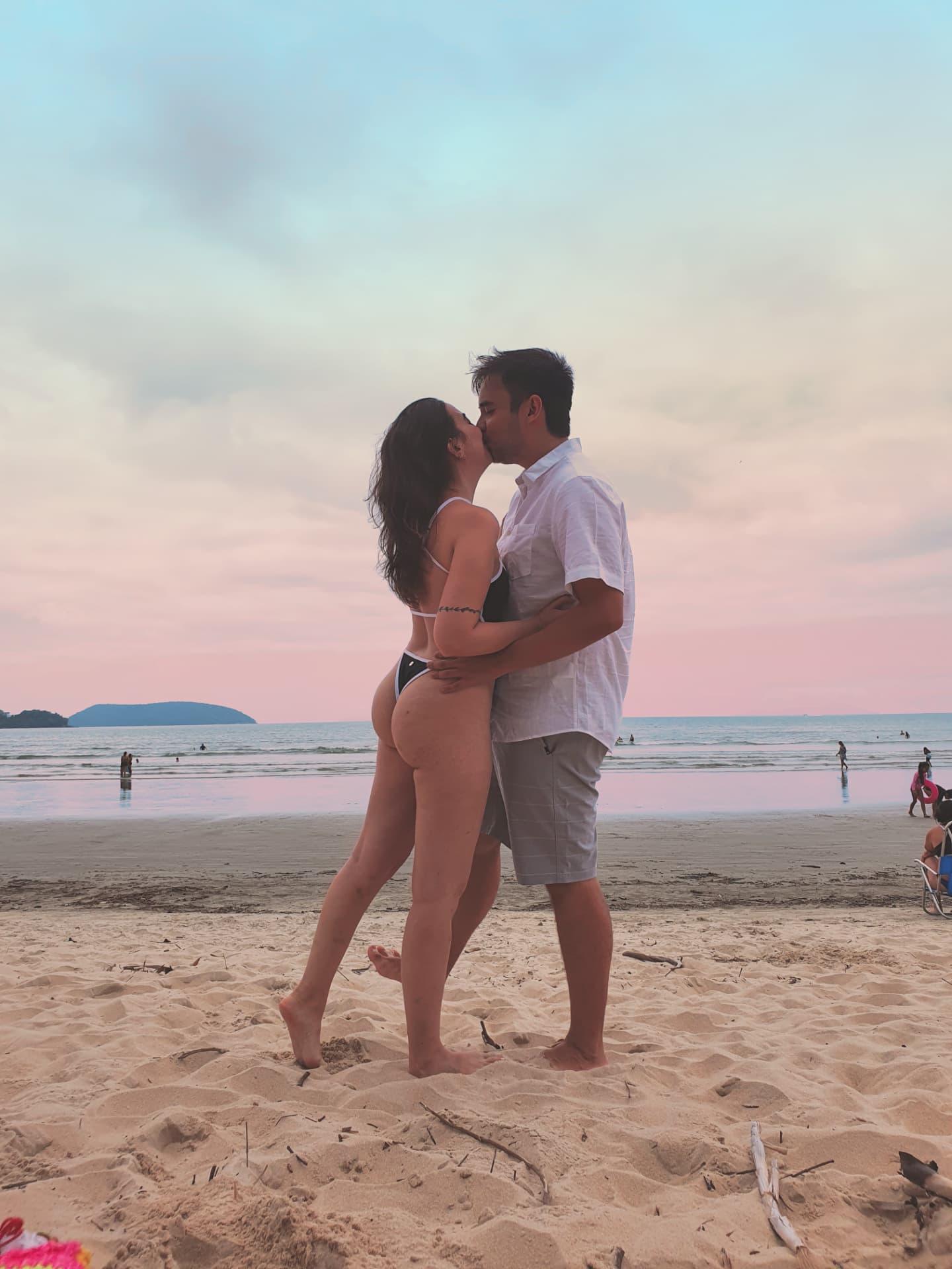 Bárbara e William se beijando na praia no fim da tarde