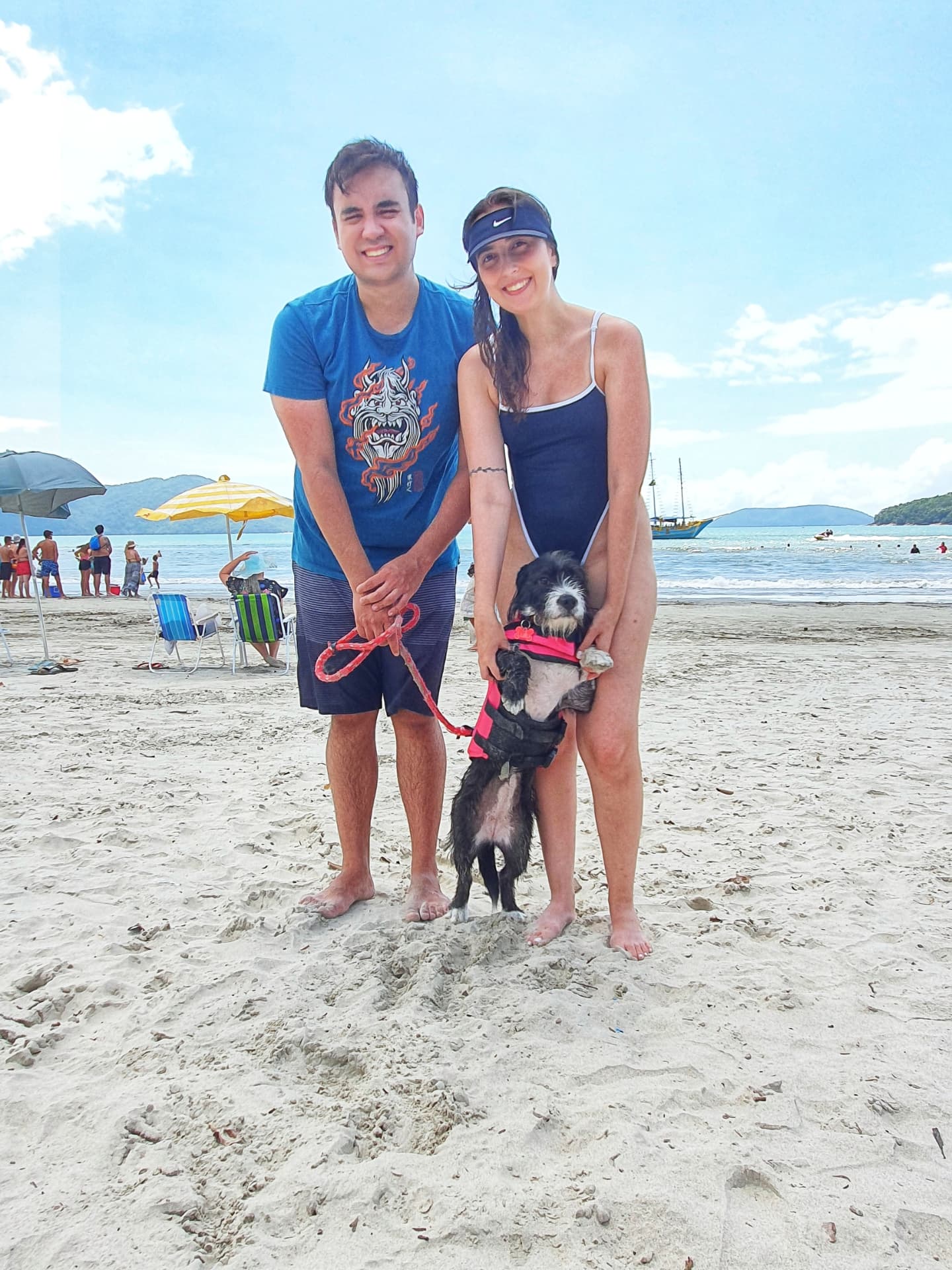 Bárbara e William na praia com a cachorrinha de colete