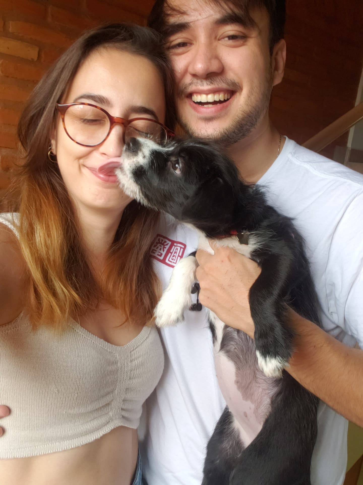 Bárbara e William com o cachorrinho lambendo o rosto dela